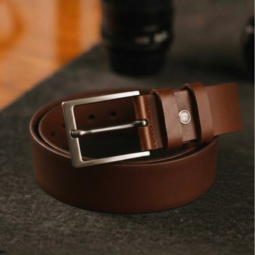 Brown leather belt with a silver buckle on a dark surface